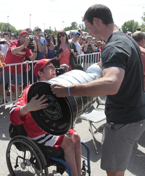 Chicago Blackhawks Captain Jonathan Toews lets his neighbour Cameron MacDonald handle the Stanley Cup at the event outside the Jonathan Toews Community Centre Friday afternoon.  Randy Turner story Wayne Glowacki/Winnipeg Free Press July 19 2013