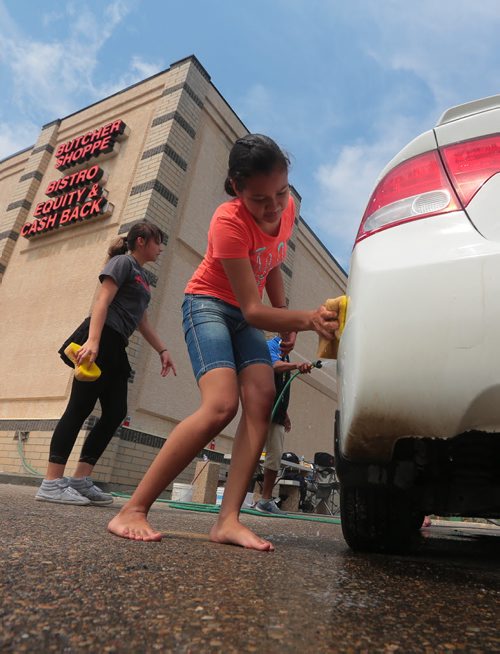 Brandon Sun Alejandra Bonilla, right, and Mia Flamand wash cars during Friday's Youth Co-operative Services kick-off held at the Heritage Co-op. (Bruce Bumstead/Brandon Sun)