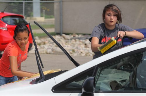 Brandon Sun Alejandra Bonilla, left, and Mia Flamand wash cars during Friday's Youth Co-operative Services kick-off held at the Heritage Co-op. (Bruce Bumstead/Brandon Sun)