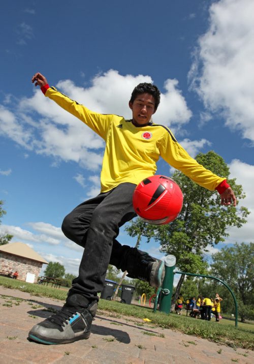 Brandon Sun 20072013 Juan Manual Aguirre bounces a soccer ball on his foot during Colombian Independence Day celebration's at the First Street spray park on Saturday afternoon. Brandon's Colombian community gathered for games, a barbecue, dancing and other events.  (Tim Smith/Brandon Sun)