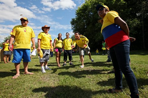 Brandon Sun 20072013 Friends play Rana, a social game popular in Colombia, during Colombian Independence Day celebration's at the First Street spray park on Saturday afternoon. The object of the game is to toss brass rings into holes worth varying points on a board. Brandon's Colombian community gathered for games, a barbecue, dancing and other events.  (Tim Smith/Brandon Sun)