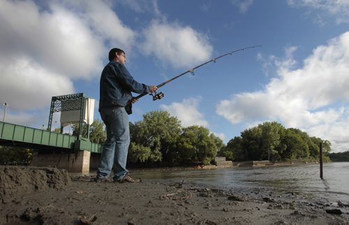 Barry Priestley, from Choiceland, Sk. while visiting family in Winnipeg try's his luck along the bank of Assiniboine River as it joins the Red River Monday morning. Wayne Glowacki / Winnipeg Free Press July 22 2013