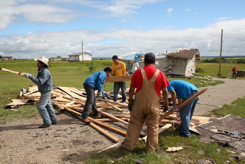 Brandon Sun 22072013 Volunteers Bill Maza, Madison Mazawasicuna, Dryden Wanbdiska, Colin Bunn and Rollie Bunn clean up the destroyed roof of a home at Sioux Valley Dakota Nation on Monday after homes were damaged by a tornado last Thursday. (Tim Smith/Brandon Sun)