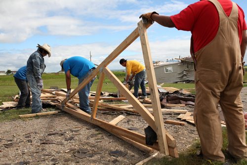 Brandon Sun 22072013 Volunteers Madison Mazawasicuna, Bill Maza, Colin Bunn, Dryden Wanbdiska and Rollie Bunn clean up the destroyed roof of a home at Sioux Valley Dakota Nation on Monday after homes were damaged by a tornado last Thursday. (Tim Smith/Brandon Sun)