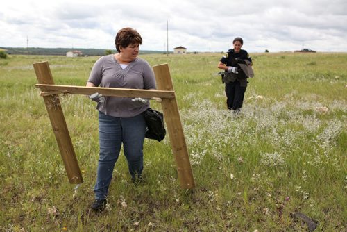 Brandon Sun 22072013 Volunteers Giselle Bell Amy Roulette clean up debris scattered across a field at Sioux Valley Dakota Nation on Monday as part of the clean-up effort after tornado destroyed one home and damaged others in the community. .  (Tim Smith/Brandon Sun)