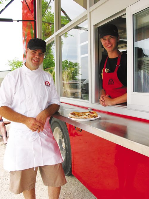 Canstar Community News July 17, 2013 - Owner Steffen Zinn (left), of Starbuck, shows off one of the freshly made pizzas baked in the wood-fired oven inside his Red Ember food truck. (ANDREA GEARY/CANSTAR)