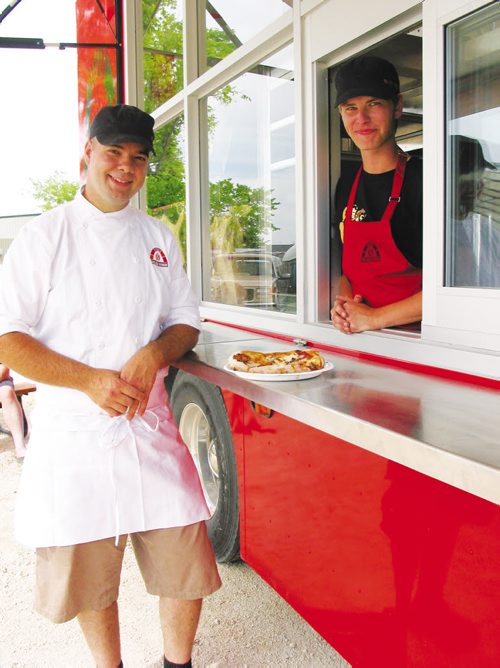 Canstar Community News JUly 17, 2013 - Owner Steffen Zinn (left), of Starbuck,  shows off one of the fresly made pizzas baked in a wood-fired oven inside his Red Ember food truck. (ANDREA GEARY/CANSTAR)