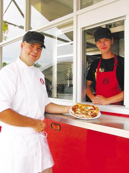 Canstar Community News July 17, 2013 - Steffen Zinn (left) holds one of the freshly made pizzas baked in the wood-fired oven inside his Red Ember food truck. (ANDREA GEARY/CANSTAR)
