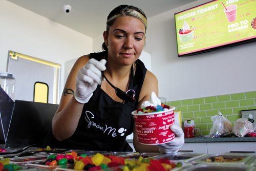 Canstar Community News July 18, 2013 -- Michelle Kindrat scoops some candy on a bowl of frozen yogurt. Kindrat, along with her husband Jeff, opened their Spoon Me franchise at 2705 Main St. on July 18. (MATT PREPROST / CANSTAR NEWS)