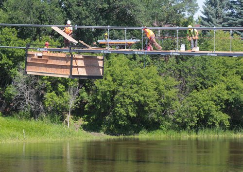 Brandon Sun Construction continues on the Souris suspension bridge as workers lay down new bridge decking on the cables over the Souris River on Wednesday. (Bruce Bumstead/Brandon Sun)