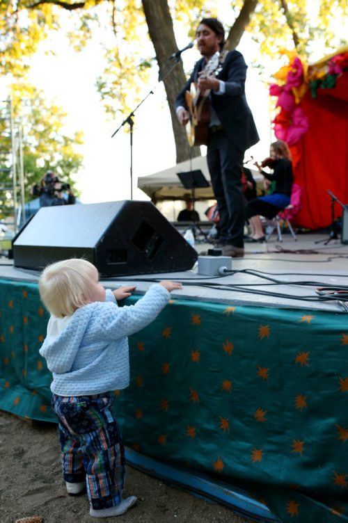 Brandon Sun 26072013 15-month-old Maxwell May-Lumgair watches as JP Hoe performs on the opening night of the 29th Annual Brandon Folk, Music and Art Festival in Brandon on Friday evening. (Tim Smith/Brandon Sun)