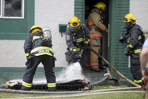 A firefighter sprays a smouldering mattress outside a fire at a two storey apartment building at the corner of Stella and Powers, Saturday, July 27, 2013. (TREVOR HAGAN/WINNIPEG FREE PRESS)