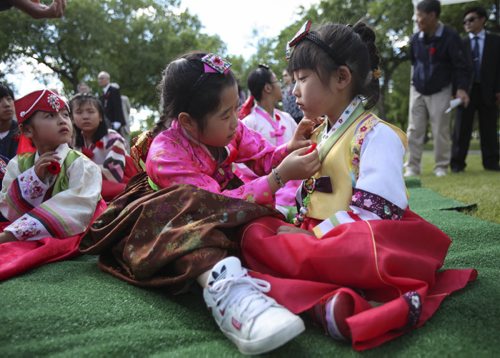 Yewon Chang (left), 8, pins a poppy onto friend Wonhee Kim, 6. They and others from Winnipeg's Korean community participated in a candle light service held in Brookside Cemetery by the Korea Veterans Association on Saturday, July 27, 2013, to mark the 60th anniversary of the Korean War ceasefire. The service also recognized the designation of 2013 as The Year of the Korea War Veteran by the Canadian government. Five hundred and sixteen Canadians gave their lives in the Korean War, which lasted three years and ended on July 27, 1953.  (MARY AGNES WELCH) (JESSICA BURTNICK/WINNIPEG FREE PRESS)