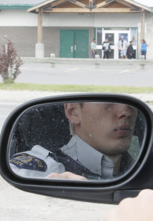 RCMP Special Const. Kyle Boisvert looks on as people sit outside the Burntwood Hotel, in Thompson, Tuesday, July 23, 2013. (TREVOR HAGAN/WINNIPEG FREE PRESS)