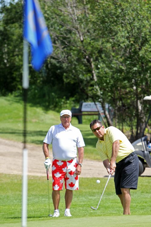 Brandon Sun 27072013 Bruce Gullett, the organizer of the inaugural Special Olympics Westman Region Golf Tournament, watches as MLA for Spruce Woods Cliff Cullen chips onto a green during the event at the Shilo Country Club on Saturday afternoon. (Tim Smith/Brandon Sun)
