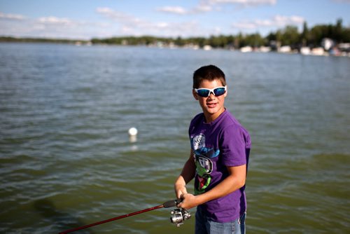 Brandon Sun 27072013 Tysne Stanski fishes off the pier at Sandy Lake on Saturday evening. (Tim Smith/Brandon Sun)
