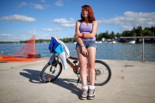 Brandon Sun 27072013 Lindsay Anderson of Brandon sits against a bike on the pier at Sandy Lake while watching friends fish on Saturday evening. (Tim Smith/Brandon Sun)