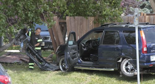A tow truck operator cleans up pieces of an SUV that crashed into a fence on Burrows Ave. near Keewatin St. near a bus stop Monday. No one was injured. Wayne Glowacki/ Winnipeg Free Press July 29 2013