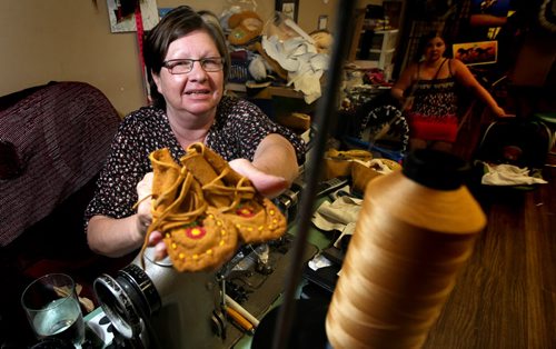 Winnipeg artisan Edna Nabess has made some mukluks and moccasins for the Royal baby. She's posing at her sewing machine holding a similar pair, the "royal" slippers are en-route to England. See Adam Wazny's story. July 29, 2013 - (Phil Hossack / Winnipeg Free Press)