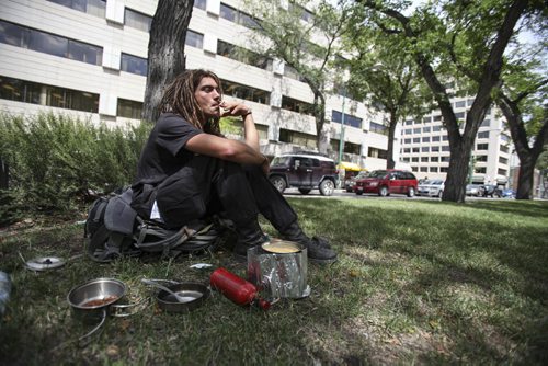 Alex, a student from Montreal, cooks a midday meal on Broadway's grassy boulevard near Hargrave St. Winnipeg is nearly a stop along the route - he is B.C. bound for the University of British Columbia, where he begins his studies in two weeks. Tuesday, July 30, 2013. (JESSICA BURTNICK/WINNIPEG FREE PRESS)
