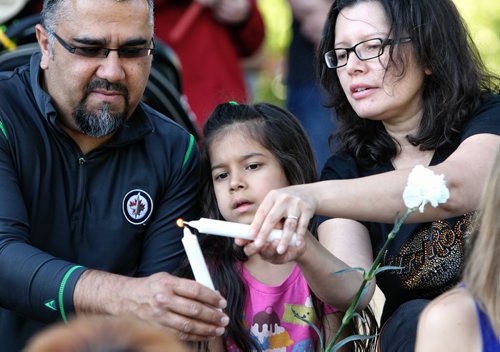 Mick and Marilyn Sidhu along with their daughter Hannah,6, attend a candlelight vigil in memory of Lisa Gibson and her two children, two-year-old Anna and three-month-old Nicholas at The Forks Thursday evening. 130801 - August 01, 2013 Mike Deal / Winnipeg Free Press