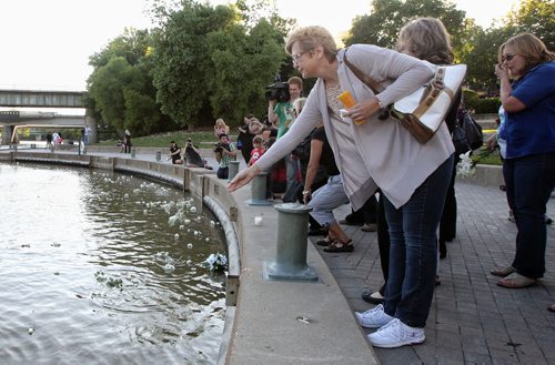Mourners attending a candlelight vigil in memory of Gibson and her two children, two-year-old Anna and three-month-old Nicholas throw white flowers into the Assiniboine River at The Forks Thursday evening. 130801 - August 01, 2013 Mike Deal / Winnipeg Free Press