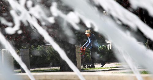 A gentleman walks behind the  fountain at the Legislature Saturday iin the sunshine.  Standup photo. August  03,, 2013 Ruth Bonneville Winnipeg Free Press