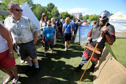A member of Vikings Vinland, a group made up of members from across Canada, the US and Europe, speaks with visitors to the Viking Village at the Icelandic Festival of Manitoba in Gimli, Saturday, August 3, 2013. (TREVOR HAGAN/WINNIPEG FREE PRESS)