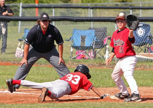 Brandon Sun 08042013 Dawson Sobry #33 of Oildome dives back to first base before the ball makes it to Kevin Burnett #21 of the North Winnipeg Pirates during their Peewee AAA Provincial Championship semifinal match at Simplot Millennium Park on Monday. (Tim Smith/Brandon Sun)