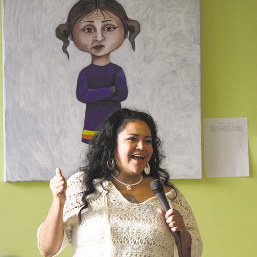 Canstar Community News Jackie Traverse speaks at the opening of her show Ever Sick at Neechi Commons, standing in front of a self-portrait. SONYA BRAUN/FOR CANSTAR NEWS