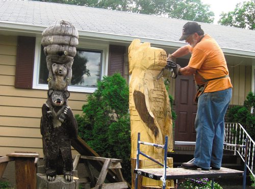Canstar Community News Aug. 7 -- Wood carver Bruce Macdonald at work in his front yard on one of his pieces. SUPPLIED PHOTO