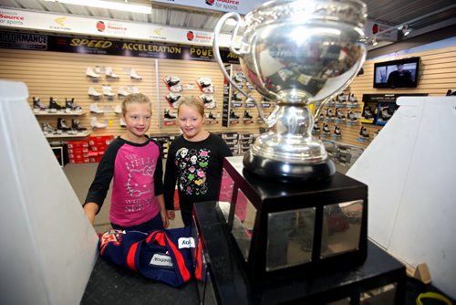Brandon Sun 09082013 Cousins Johanna Fleger and Julia Fleger get a close look at the American Hockey League championship trophy the Calder Cup during an appearance at Brandon source for Sports on Friday. AHL player Brett Skinner, who was part of the 2013 Calder Cup winning team the Grand Rapids Griffins brought the trophy to the sports store for fans to have a look at.  (Tim Smith/Brandon Sun)