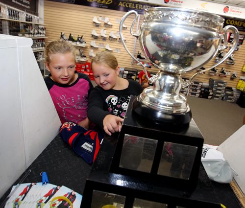 Brandon Sun 09082013 Cousins Johanna Fleger and Julia Fleger get a close look at the American Hockey League championship trophy the Calder Cup during an appearance at Brandon source for Sports on Friday. AHL player Brett Skinner, who was part of the 2013 Calder Cup winning team the Grand Rapids Griffins brought the trophy to the sports store for fans to have a look at.  (Tim Smith/Brandon Sun)