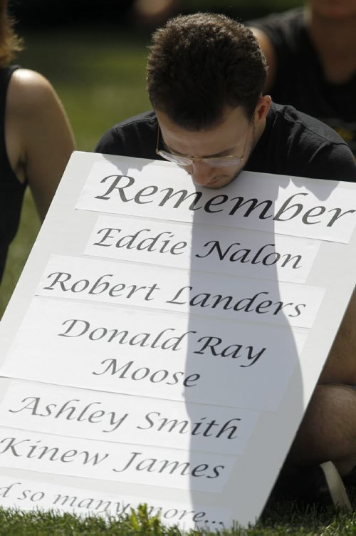 A man holds a sign with names listed as a tribute during National Prisoner Justice Day, Saturday, August 10, 2013. (TREVOR HAGAN/WINNIPEG FREE PRESS)