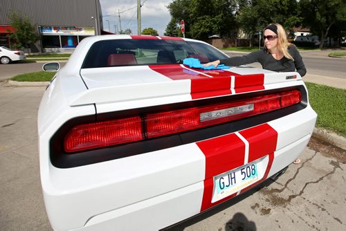 Brandon Sun 10082013 Angela Blue dries off her husbands Dodge Challenger after washing it at the car wash on Park Ave. on a sunny Saturday morning. (Tim Smith/Brandon Sun)