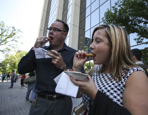 The Downtown BIZ launched the third annual ManyFest on Broadway today with a food truck war between businesses Pimp My Rice, Habanero Sombrero and On A Roll. Olga Pogrebinskaia (right) and Dave Stone came over from Portage Place on their lunch hour to sample the egg rolls from Pimp My Rice. Wednesday, August 14, 2013. (ELIZABETH FRASER) (JESSICA BURTNICK/WINNIPEG FREE PRESS)
