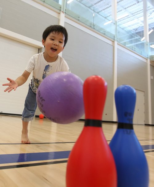 Brandon Sun 16082013 Aiden practices his bowling skills while playing in the BU Healthy Living Centre with other children from the BU Early Leaning Centre on Friday afternoon. (Tim Smith/Brandon Sun)