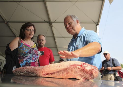 International cooking instructor and master BBQ teacher Jim Johnson explains the best way to prepare beef brisket to passersby in the BBQ cook-off area. The competition will be judged tomorrow as part of the second annual BBQ and Blues Festival at the Red River Exhibition Grounds. Saturday, August 17, 2013. (JESSICA BURTNICK/WINNIPEG FREE PRESS)