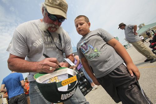 Marc Springer of Snortin Boar Transport (left), who is perhaps better known from Shipping Wars on A&E, signs a ball cap for nine-year-old fan Easton Henry of Stonewall, Man. He's on site this weekend during the Show and Shine at the second annual BBQ and Blues Festival this weekend at the Red River Exhibition Grounds. Saturday, August 17, 2013. (JESSICA BURTNICK/WINNIPEG FREE PRESS)