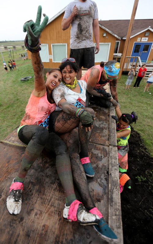Poonam Randhawa and Lillian Mendoza pose on the Wall of Shame while the rest of their team make their way up the obstacle during the Dirty Donkey Run, a 5km run through a muddy obstacle course, at Springhill, Saturday, August 17, 2013. (TREVOR HAGAN/WINNIPEG FREE PRESS)