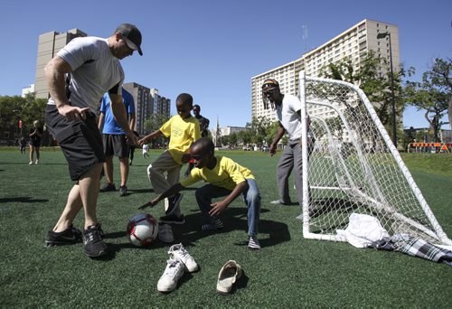 Nine-year-old Bienfait (centre) guards the goal with help from a teammate, police officer Shawn Gallant (left), during a soccer match in Winnipeg's Central Park. Organized by the Winnipeg Police Cadets, the game marked the third annual Kickin' It With Cadets event on Wednesday, August 21, 2013. (JESSICA BURTNICK/WINNIPEG FREE PRESS)