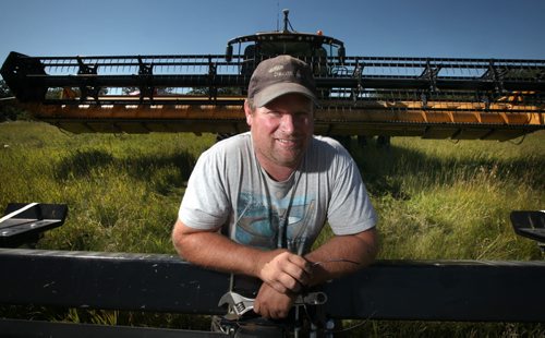 Curtis McRae poses in front of his combine Wednesday. He said theyre running about three weeks late because of the late spring and the cool weather in July, which slowed crop growth. Murray McNeill story August 21, 2013 - (Phil Hossack / Winnipeg Free Press)