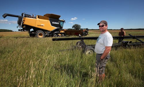 Curtis McRae watches as his brother Mac drives one of their new combines into a field of Canola to try and harvest the crop. He said theyre running about three weeks late because of the late spring and the cool weather in July, which slowed crop growth. Murray McNeill story.  August 21, 2013 - (Phil Hossack / Winnipeg Free Press)
