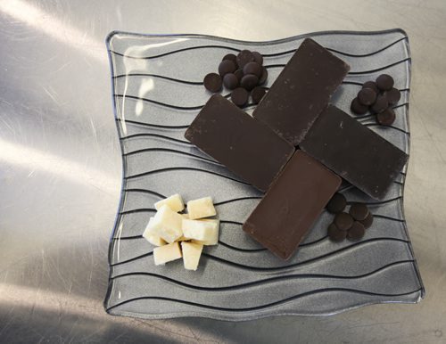 Kyle Otter, a chef apprentice at the Red River College School of Hospitality and Culinary Arts, puts together chocolate dipped parmigiano-reggiano (chocolate covered parmesan cheese). The raw ingredients required are parmigiano-reggiano cheese (bottom left), and four chocolate varieties (clockwise from bottom): milk chocolate, smooth chocolate, medium chocolate, and extra dark chocolate. Thursday, August 22, 2013. (JESSICA BURTNICK/WINNIPEG FREE PRESS)