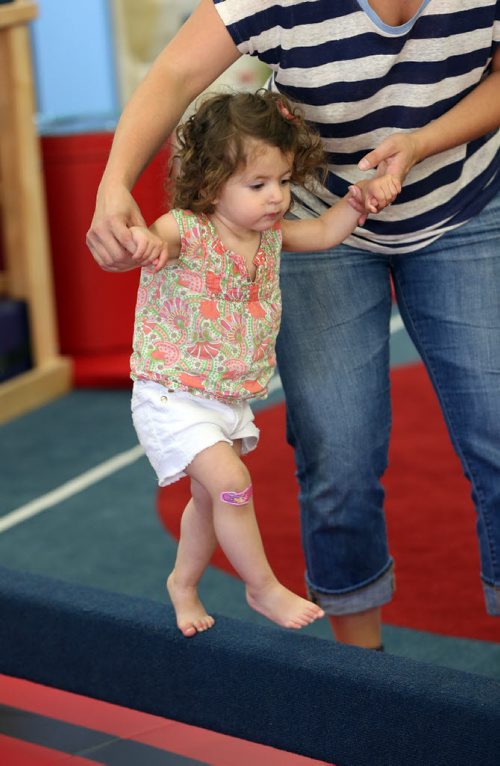 Brooke Babakhanians  age 18 months walks balance beam with help from her mother Alanna -Childhood Obesity Äì The My Gym location specializes in fitness for infant and young children  - storey by Randy Turner fr 49.8  KEN GIGLIOTTI / Aug 22 2013 / WINNIPEG FREE PRESS