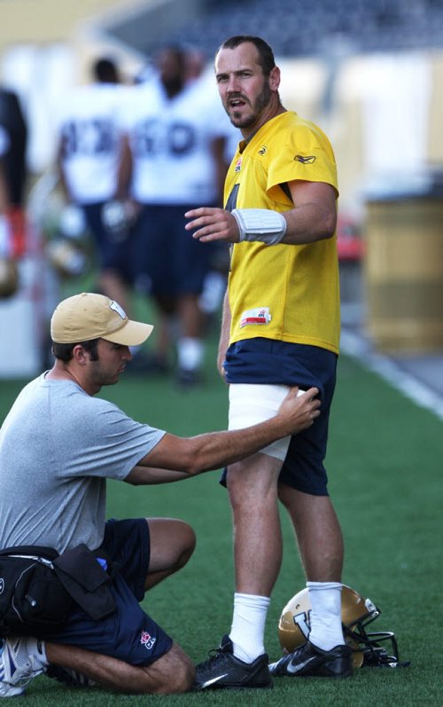 Winnipeg Blue Bombers quarterback Buck Pierce gets a tensor bandage applied by head athletic therapist Alain Couture on the field during practice Thursday at Investors Group Field -See story- August 22, 2013   (JOE BRYKSA / WINNIPEG FREE PRESS)