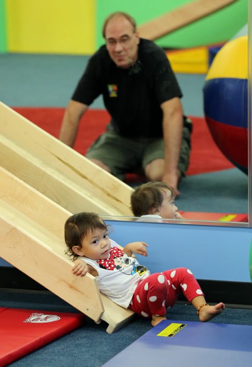 Shawn Holes watches his 19 month daughter Mahailia  fisrt climb up the slide then slide down the slide ramp- Childhood Obesity Äì The My Gym location specializes in fitness for infant and young children  - storey by Randy Turner fr 49.8  KEN GIGLIOTTI / Aug 22 2013 / WINNIPEG FREE PRESS