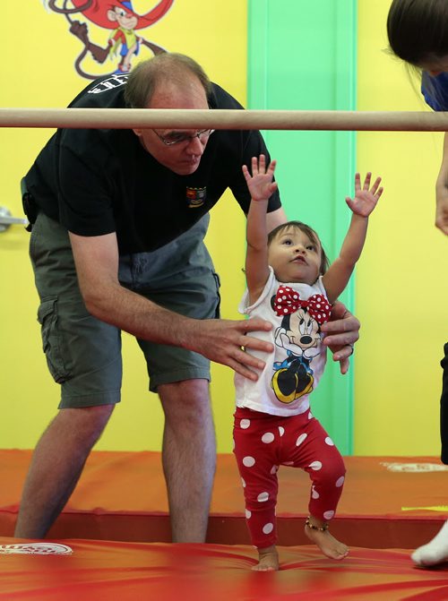 Shawn Holmes helps his 19 month daughter reach the chinup bar - Childhood Obesity Äì The My Gym location specializes in fitness for infant and young children  - storey by Randy Turner fr 49.8  KEN GIGLIOTTI / Aug 22 2013 / WINNIPEG FREE PRESS