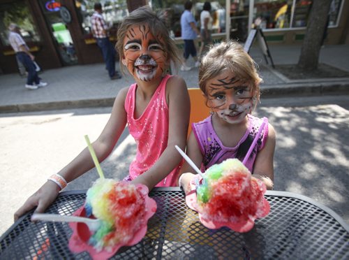 Sisters Jaydyn Gilmore, 8, and Kalley, 6, from St. Jeanne make a purr-fect pair with matching tiger face paint and larger-than-usual rainbow ice confections at the festival. Established in 1967, the Morden Corn and Apple Festival is the town's chief attraction, and is always held in the fourth week of August. Friday, August 23, 2013. (JESSICA BURTNICK/WINNIPEG FREE PRESS)