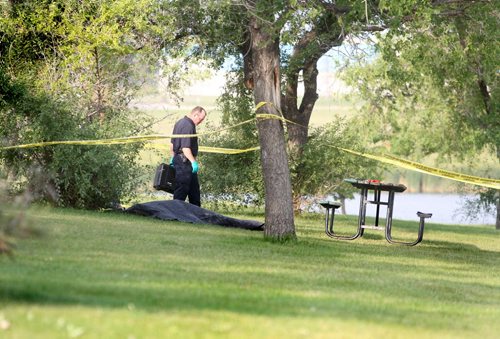A Police Officer inspects a body found in Woodsworth Park Saturday morning.   August  24,, 2013 Ruth Bonneville Winnipeg Free Press